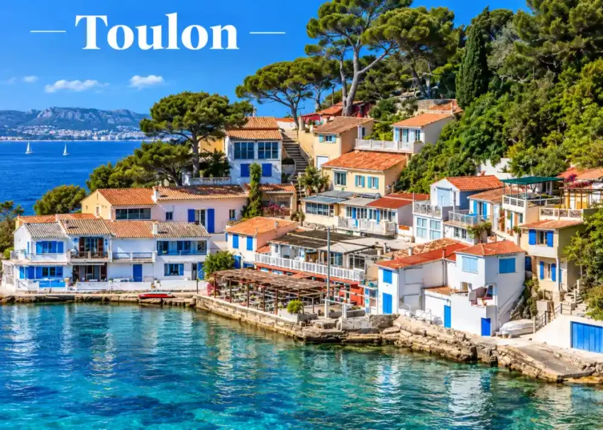 Vue panoramique d'un village maritime avec maisons a toits oranges et balcons bleus sur une colline au bord d'une mer azur et arbres verts