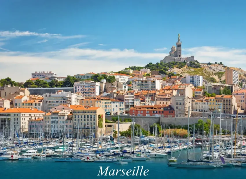 Immobilier à Marseille en 2026 : hausse des prix ou retournement du marché ? 3 Vue latérale du port de marseille avec une marina remplie de voiliers, immeubles colorés et une colline surmontée par une grande eglise au sommet