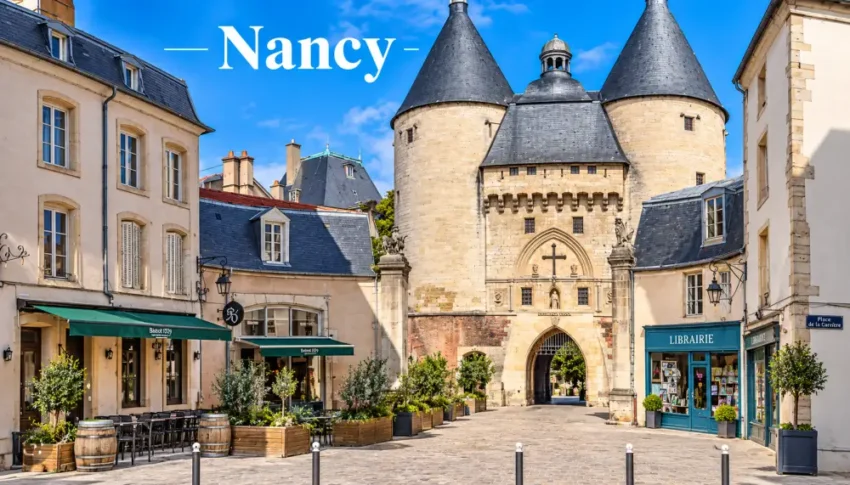 Vue urbaine de Nancy avec une porte fortifiée à tours rondes en pierre, façades pastel, cafés en terrasse et librairie bleue.