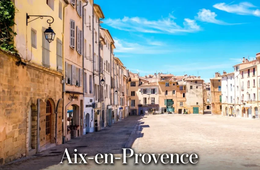 Immobilier à Aix-en-Provence en 2026 : le marché haut de gamme résiste-t-il à la baisse ? 1 Vue d'une rue pavée bordée de maisons en pierre et stucco crème, volets blanchis, lampadaires et ciel bleu clair.